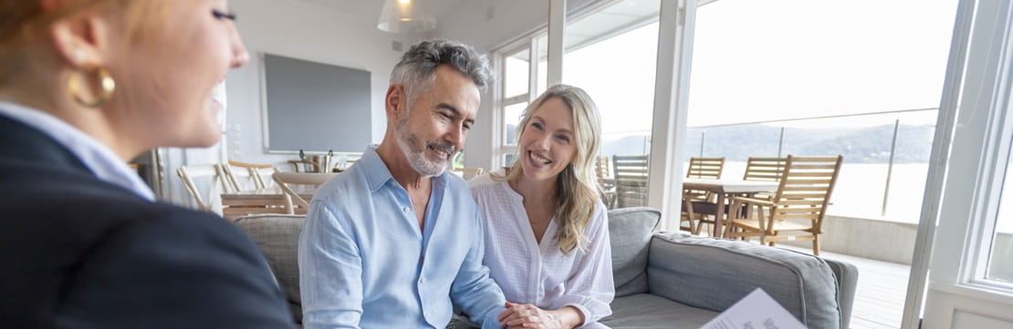 Happy mature couple meeting financial advisor seated in their home